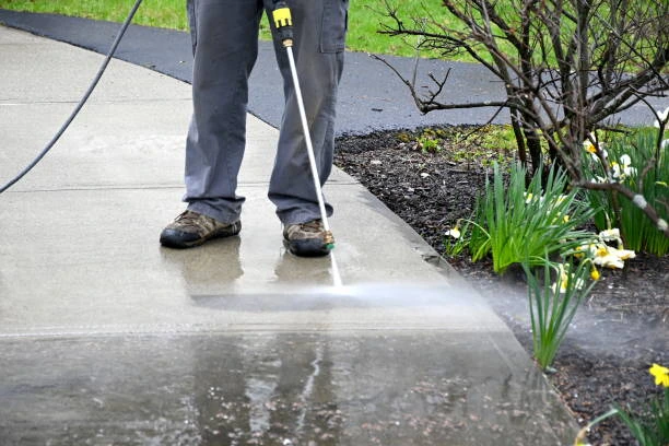 Pressure washing a concrete sidewalk to remove dirt, mold, and algae buildup in Massachusetts
